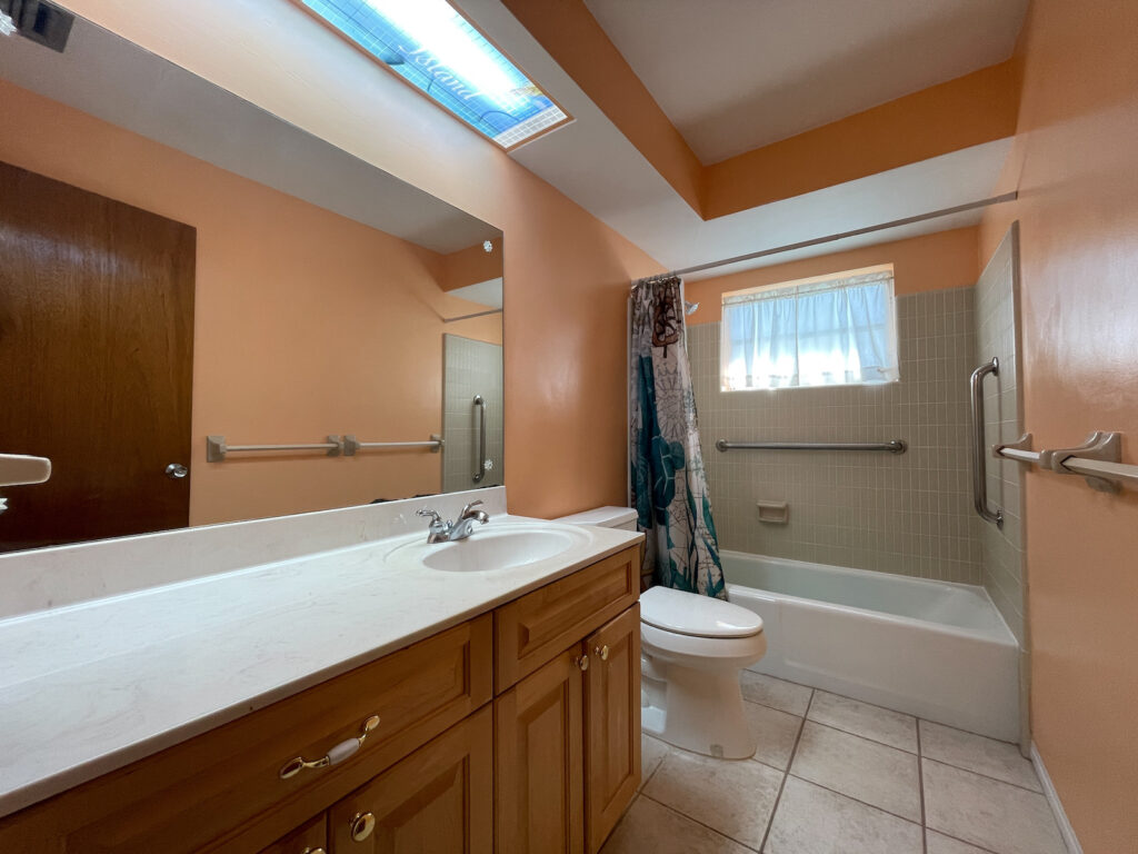 Outdated peach bathroom with wood vanity and soffit ceiling before remodel in Treasure Island