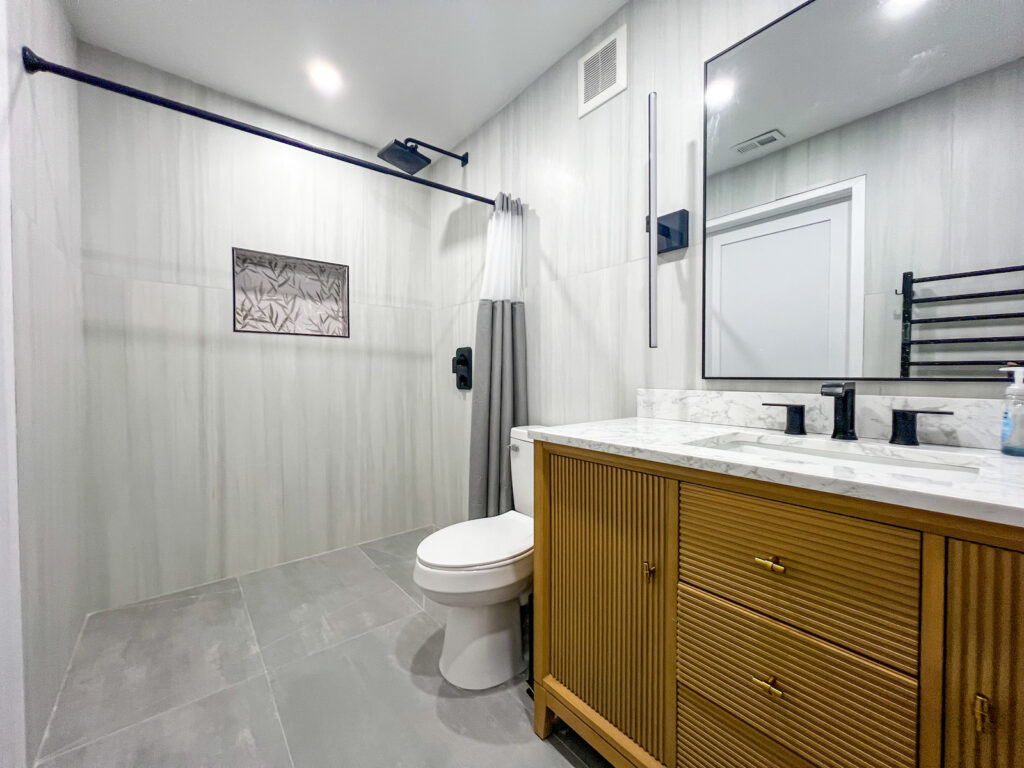 Modern bathroom remodel in Clearwater FL featuring zero entry shower, fluted wood vanity and matte black fixtures