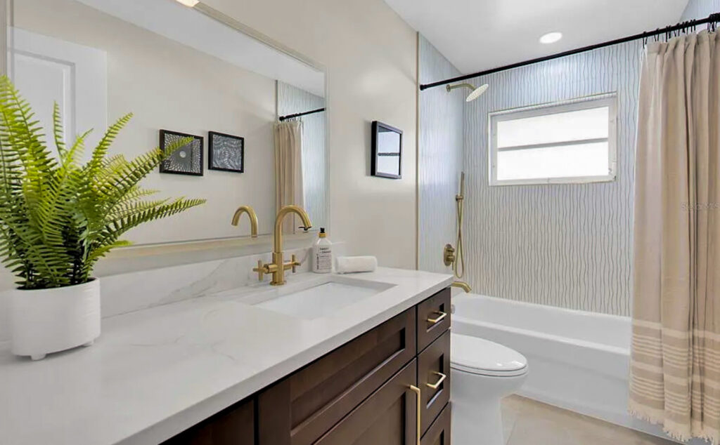 Modern bathroom remodel with gold fixtures and Amalfi gold ceramic wall tile in Treasure Island